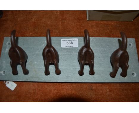 A set of novelty coat hooks in the form of dogs tails on a slate base