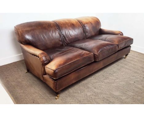 HOWARD STYLE SOFA, faded tan leather with brass castors, 75cm H x 202cm x 110cm.