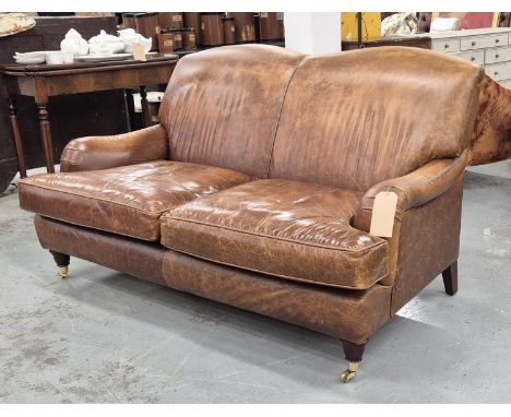 HOWARD STYLE SOFA, brown leather with brass front castors, 90cm H x 160cm W x 97cm D.
