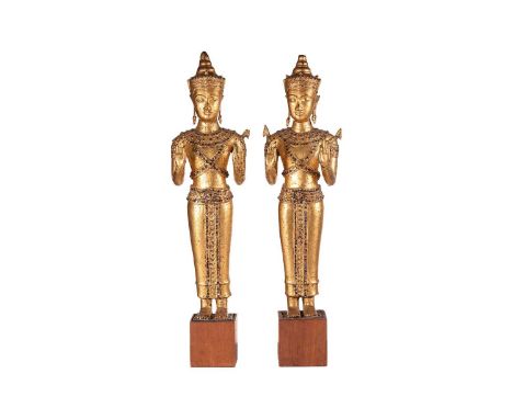 A pair of Thai cast and gilt bronze figures of Nats, 20th century, each in Abhaya Mudra, the hems of their robes set with col