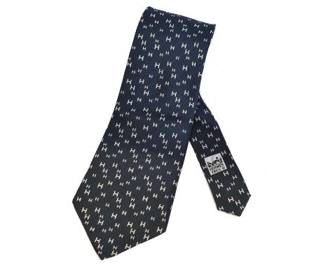 A Hermès silk tie, A Hermès silk tie, the monogrammed white pattern atop a navy background.Overall condition goodSigns of onl