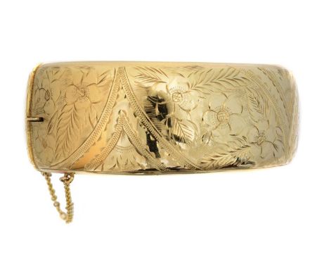 A 9ct gold hinged bangle, A 9ct gold hinged bangle, with floral engraving and push piece clasp, hallmarks for Birmingham, 196