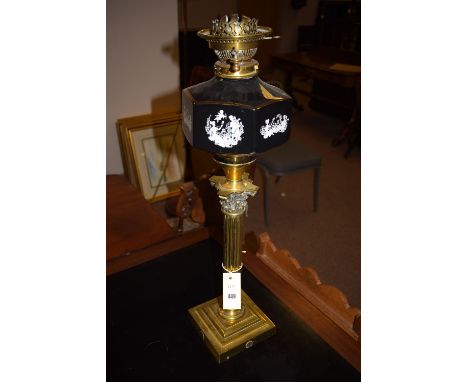 A large brass corinthian column pattern table oil lamp, with hexagonal black glass reservoir (no chimney or shade).