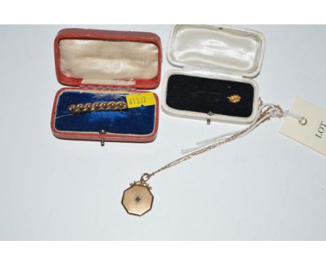 A gold mounted octagonal locket pendant on chain; a bead decorated brooch; and a tie pin.