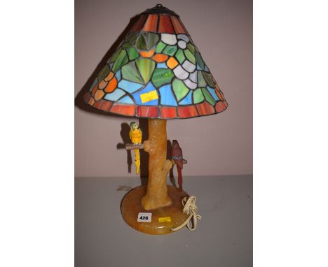 A 1930's alabaster table lamp in the form of a tree trunk, with two cold painted bronze parakeets, one in red, the other in b