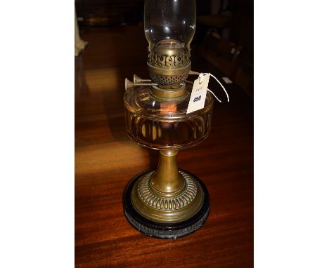 A late Victorian table oil lamp, fitted a clear glass chimney and clear glass reservoir, raised on a metal column and raised 