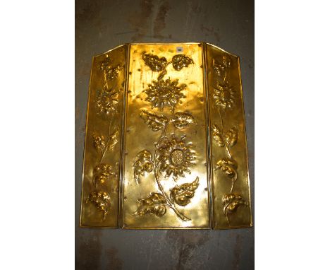 A brass folding fireguard with embossed floral decoration.