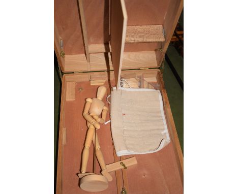 A modern artist's paint box with fitted interior, containing a wooden life study model.