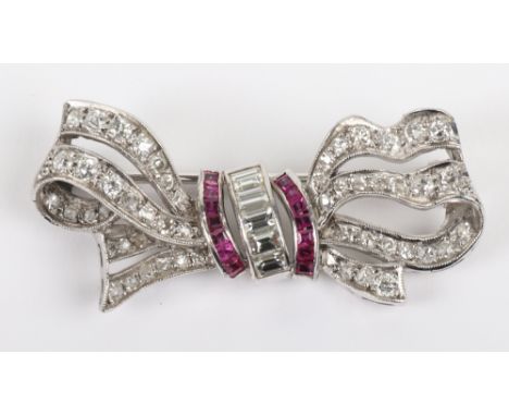 A white metal, diamond and ruby bow brooch, centre channel set with five baguette cut diamonds (0.4 carat total), between cur