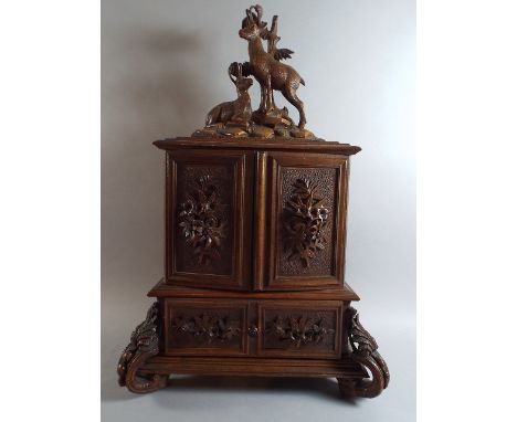 A Carved Black Forest Collectors Cabinet with Pierced Raised Floral Mounts to Panelled Doors which Open to Reveal Four Drawer