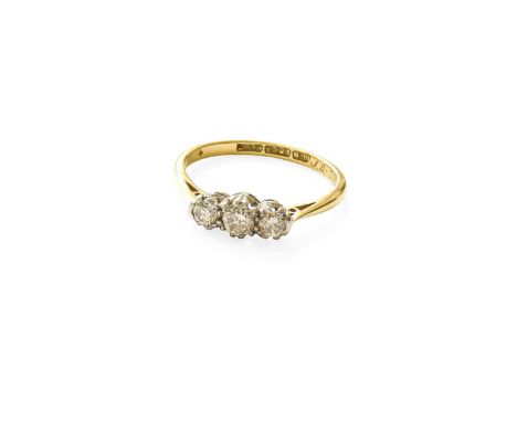 A Diamond Three Stone Ring, the old cut diamond flanked by round brilliant cut diamonds, in white claw settings, to a yellow 
