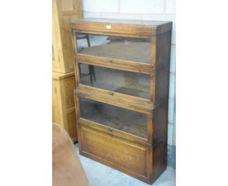 An Oak Globe Wernick " Classic" 4 tier stacking bookcase with 3 glazed sliding doors above a panelled door. 