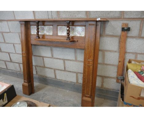An Early 20th century oak fire surround with a tiled back above a secondary shelf with outset barley twist columns.