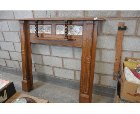 An Early 20th century oak fire surround with a tiled back above a secondary shelf with outset barley twist columns.