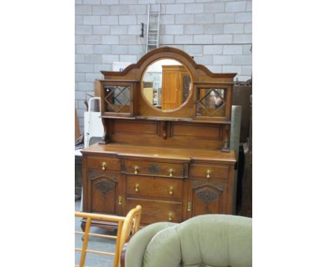 An Early 20th century art nouveau oak mirror back sideboard , the circular mirror flanked by two glazed cabinets on a shaped 