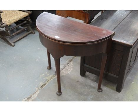 A Georgian walnut bow front folding tea table with a shaped frieze , tapering legs and pad feet.