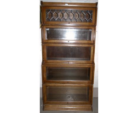 An oak 5 height sectional bookcase in the style of Globe-Wernicke, the top enclosed by leaded diamond doors over plain glazed