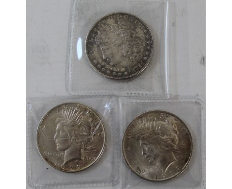 Two one dollar peace coins and an engraved Morgan coin