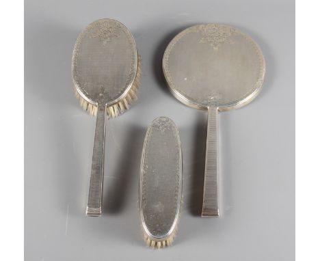 A silver backed three-piece dressing table set with engine turned and engraved decoration