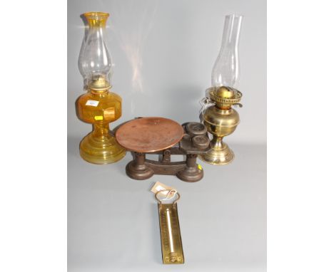 A moulded brass pedestal oil lamp, a brass pedestal oil lamp, a set of kitchen scales with weights and a brass kitchen thermo