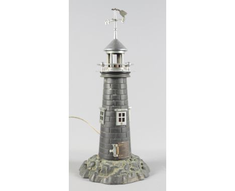 A cast metal table lamp modelled as a lighthouse on rocky base