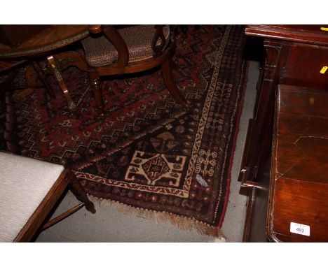 A Shiraz carpet decorated stylised animals and foliage on a hexagonal stepped brick red ground with brown spandrels, 115" x 8