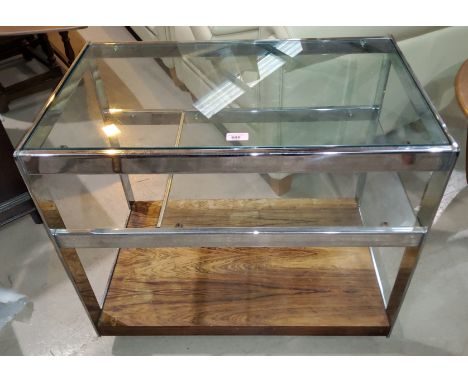 A 1960's chrome glass and rosewood drinks trolley by Merrow Associates, having glass top and shelf, rosewood undershelf and c