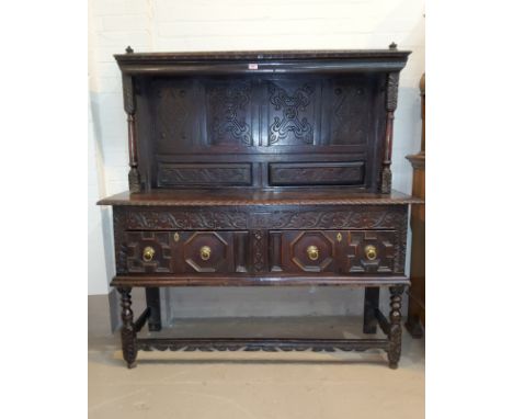 A carved oak dresser of 18th century origins with raised back shelf on turned columns, 2 drawers to the base with geometric m