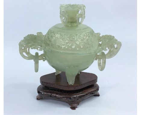 A covered vase in jade coloured hardstone with intricate carving and piercing, height 13 cm, on carved hardwood base.&nbsp;&n