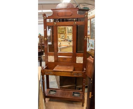 A Victorian hall stand with two ceramic panels, central mirror and original brass hooks, on turned legs