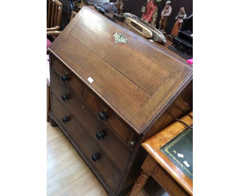 A George III oak bureau; two above and two drawers, knob handles, drop down writing top, on bracket feet