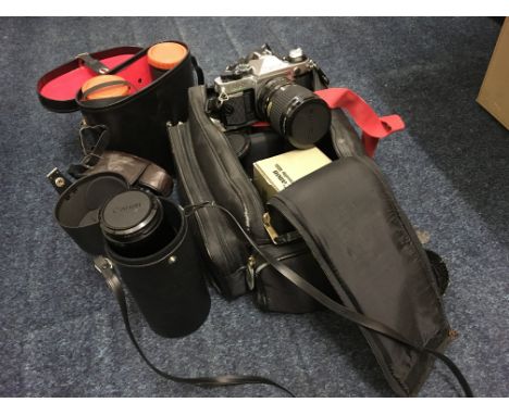 A box containing various cameras and equipment, including a Canon, Canon Skylight lens, pair of binoculars and tripod stand. 