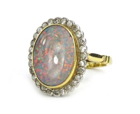 An opal and diamond ring, with central opal in rub over setting, 16mm x 12mm, surrounded by tiny diamonds, on pierced ret wor