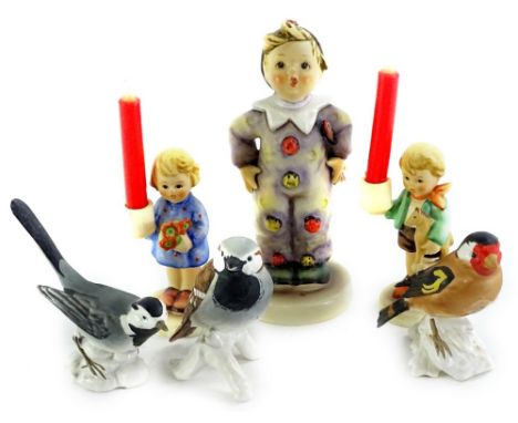 A collection of Goebel figures, to include a Hummel figure of a boy, dressed as a clown, a pair of candlesticks and three Goe
