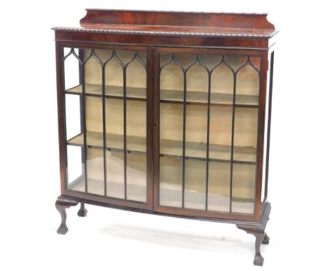 An early 20thC mahogany bow fronted display cabinet, the raised back above a gadrooned frieze and two astragal glazed doors, 