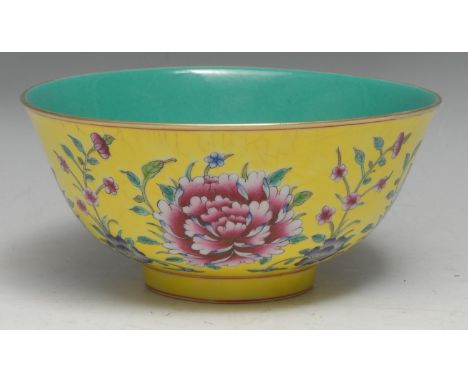 A Chinese monochrome porcelain circular bowl, painted in polychrome enamels with chrysanthemums and other flowers on a yellow