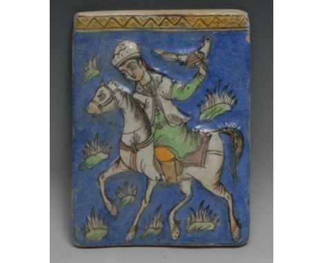 A Persian rectangular tile, moulded and painted in the typical Qajar taste with a falcolner on horseback, 23cm x 18cm 