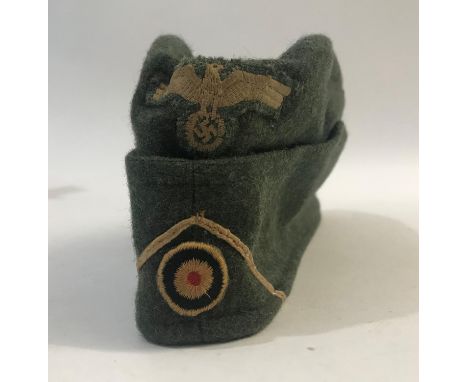A GERMAN ARMY FOLDING SIDE CAP. In khaki fabric with an eagle with wings outstretched over a swastika, braid and roundel, the