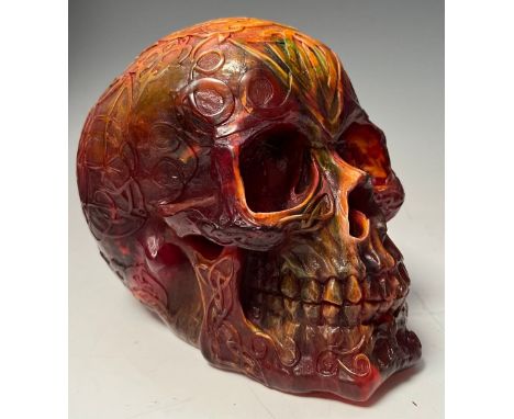 An amber coloured resin Skull, all over decorated with Celtic scrolls and motifs, approx. 13.5cm high 