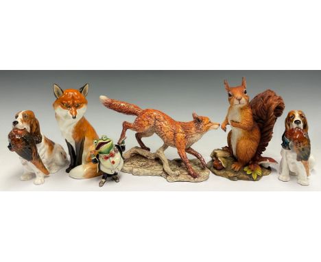 A Royal Doulton model, of a spaniel with a pheasant, 13.5cm high; another; a Royal Worcester model, of a seated fox, 19cm hig