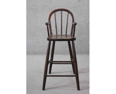 A vintage hooped back Windsor style child's high chair on shaped circular section stretchered supports. H.83. W.32 D.33 cm. 
