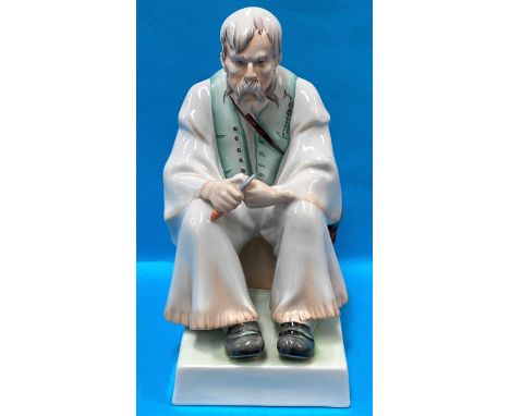 A Hungarian Zsolnay Pecs porcelain figurine of a seated old man carving wood 