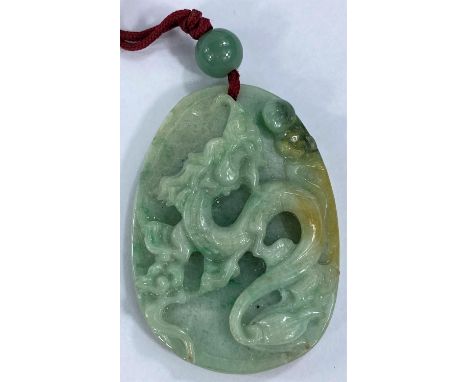 A Chinese pendant in jade coloured hardstone carved with a dragon 