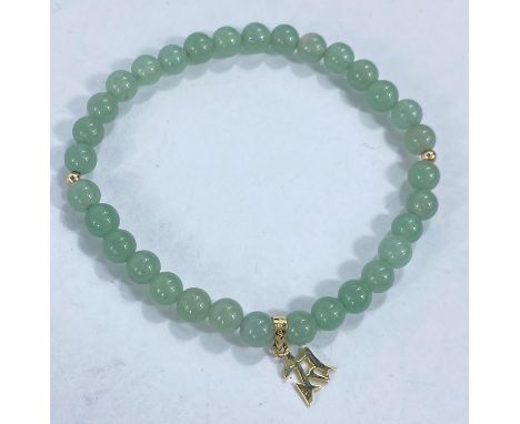 A bracelet formed from celadon green jade coloured rounded beads with gold pendant attached, stamped '10k', 10.3gms 