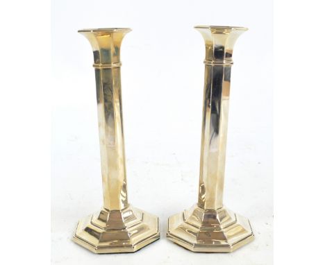 A&J ZIMMERMAN LTD; a pair of George V hallmarked silver candlesticks of octagonal form raised on stepped loaded bases, Birmin