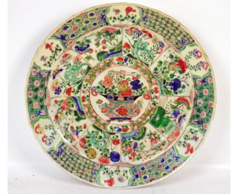 A Chinese Kangxi Famille Verte dish centred with a basket of flowers within a border of flowering branches and rock work in f