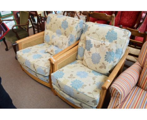 A pair of Ercol blond oak easy chairs with bergère sides, ball feet, upholstered in floral fabric (2).