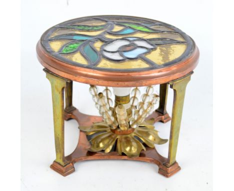 An Arts and Crafts copper and brass table lamp with circular floral decorated leaded stained glass top, rectangular upright a