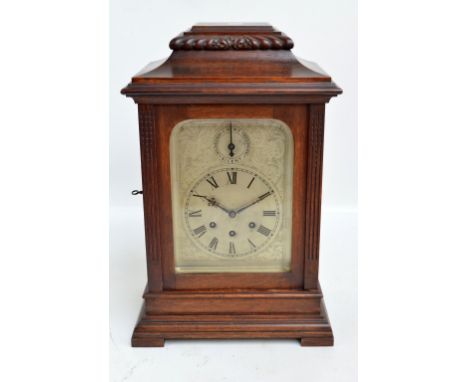 A c.1900 oak bracket clock with shaped case and engraved arched silvered dial set with Roman numerals and chime/silent dial a