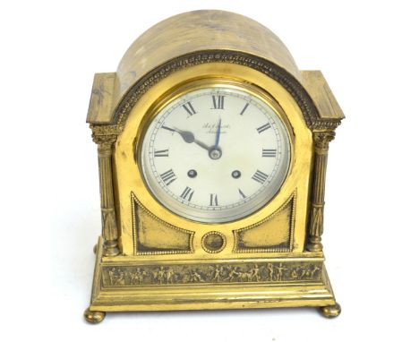 A brass arched top mantel clock with two fluted Corinthian columns, a frieze of cherubs, raised on bun feet, the brushed meta
